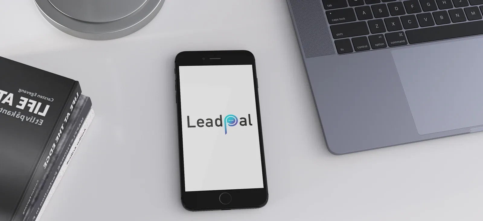 A phone showing the LeadPal logo on a desk next to a laptop.